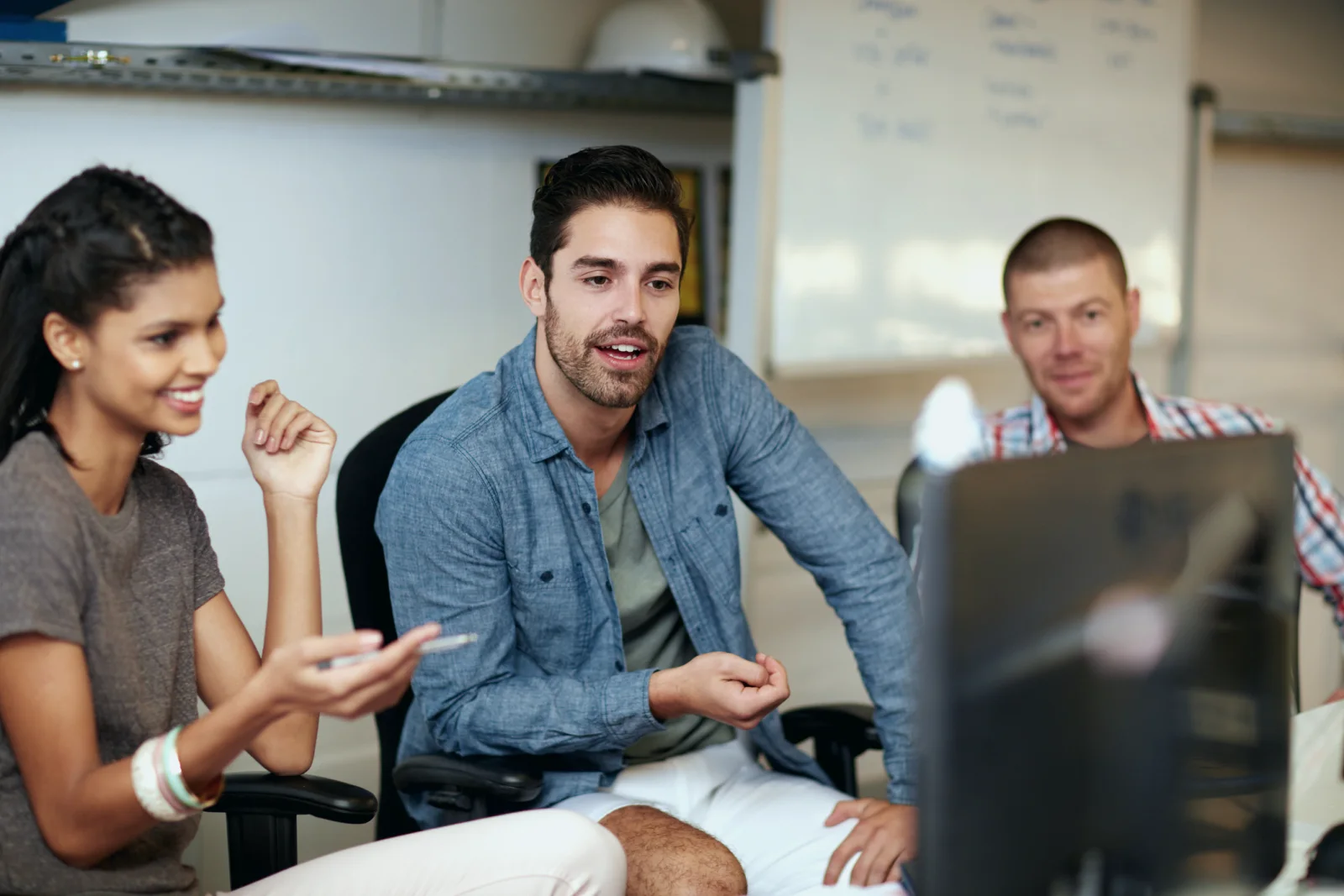 A team collaborating in front of a computer monitor.