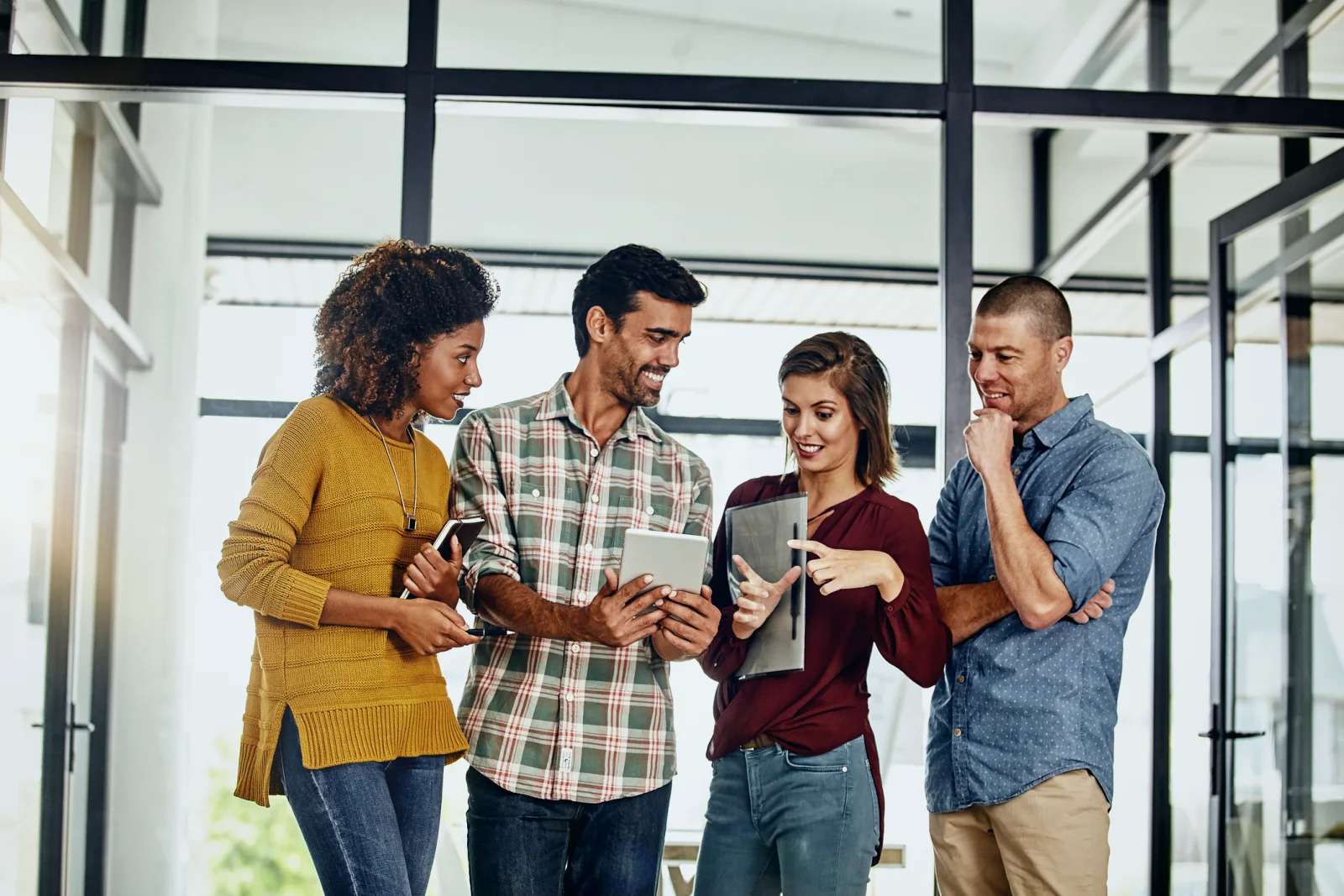 Four colleagues looking at a tablet together in an office.