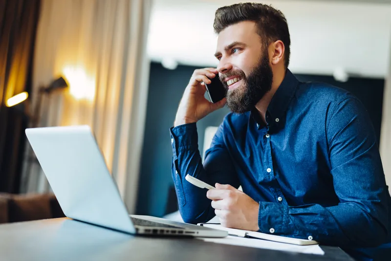 Smiling team member on a phone call at a laptop in a modern office